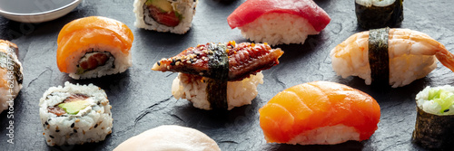 Sushi panorama. Nigiri with eel, salmon, shrimp on a black background, Japanese food on a plate at an Asian restaurant photo