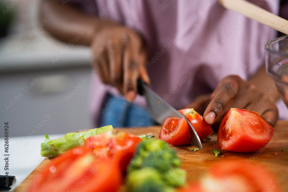 Young African woman in kitchen. Close up of woman making salad.