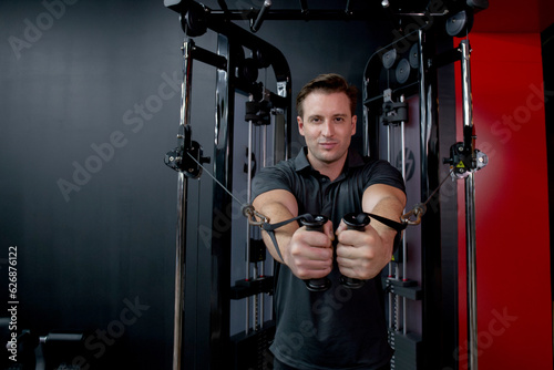 Young caucasian man workout with strength training and determination with fitness gym machines, man stretch hands and exercise with motivation in fitness, sport and health, strong and flexibility.