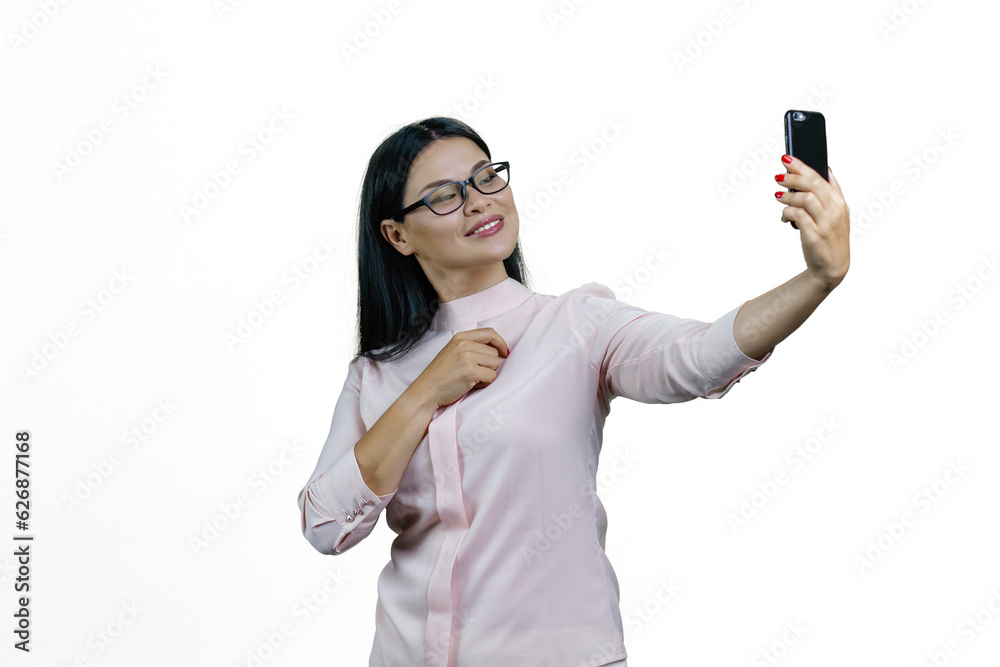 Attractive young asian woman in glasses is taking a selfie on frontal camera. Isolated on white background. Attractive young asian woman in glasses is taking a selfie on frontal camera. Isolated on white background.
