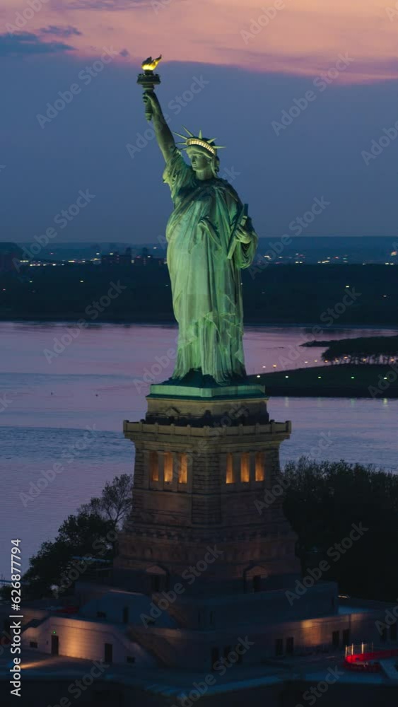 Vertical Screen: Aerial Fly-By Around the Statue of Liberty. Helicopter Footage of the Patriotic Monument in Beautiful Sunset Setting, Standing on a Liberty Island in New York City Harbor