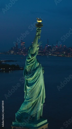 Vertical Screen:Aerial Helicopter Cinematic View of the Statue of Liberty with Manhattan Skyline Cityscape in the Evening. Panorama of New York City Skyscrapers and Jersey City Buildings at Sunset