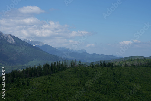 Góry piękne zdjęcie przedstawiające krajobraz górski wysokie szczyty i doliny nad którymi jest niebieskie niebo z kłębiącymi się chmurami. 