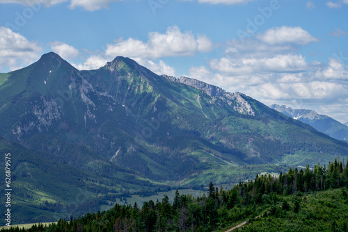 Góry piękne zdjęcie przedstawiające krajobraz górski wysokie szczyty i doliny nad którymi jest niebieskie niebo z kłębiącymi się chmurami.  © klumb