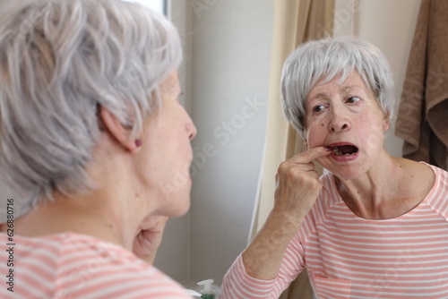 Senior woman checking the inside of her mouth 