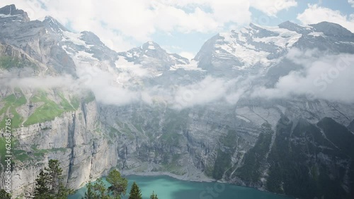 Aerial drone view of Oeschinensee Oeschinen Lake alpine lake with cliffs and snowy peaks above