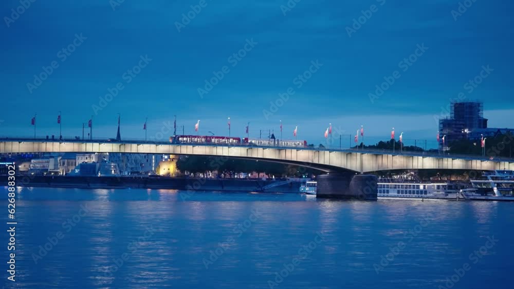 Panoramic view of u-bahn train passing on illuninated Deutz bridge in Cologne at night, cinematic shot
