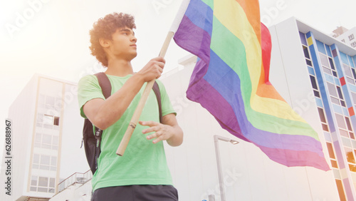 Smiling handsome young man with LGBT flag in his hands