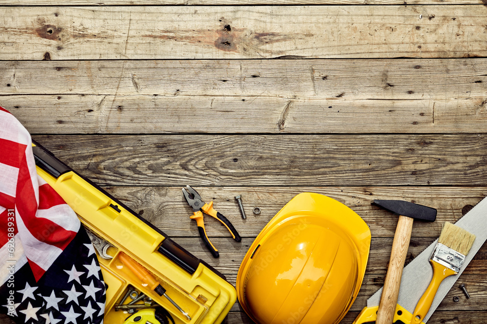 Happy Labor Day concept. Flat lay composition with USA flag, safety helmet, different worker tools on wooden background.