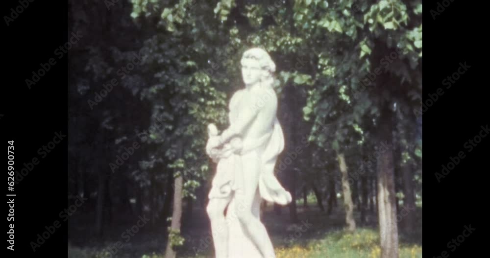 Ancient white woman statue in summer green park, close up. Antique sculpture landmark in garden. Stone monument in landscape. Archive travel. Archival vintage color film. Old retro 1980s Moscow Russia
