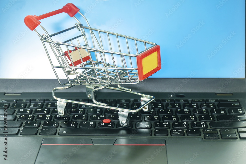 small shopping cart on laptop and blue computer screen background concepts shop on line