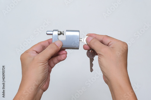 Close-up: A man's hand is about to open a padlock with a key