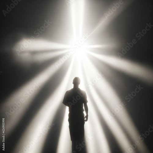 The silhouette of a man without one arm stands in the rays of light. The concept of hope, humility and faith in the best.