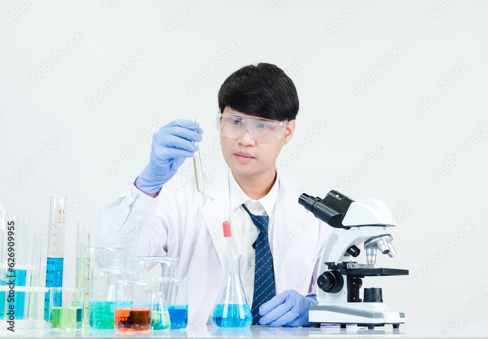 Asian man student scientist Wearing a doctor's gown in the lab looking hand at chemist. caused by mixing reagents in scientific research laboratories with test tubes and microscope on the table