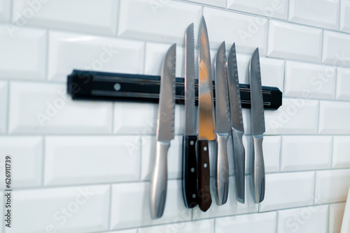 A close-up of a set of knives hanging on the wall in the professional kitchen of a sushi restaurant 