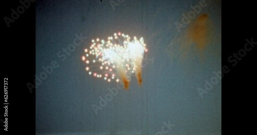 People crowd watching fireworks on city buildings background at night. Bright fireworks explode in blue sky. Holiday celebration at event. Archival vintage color film. Archive video. Old retro 1980s 