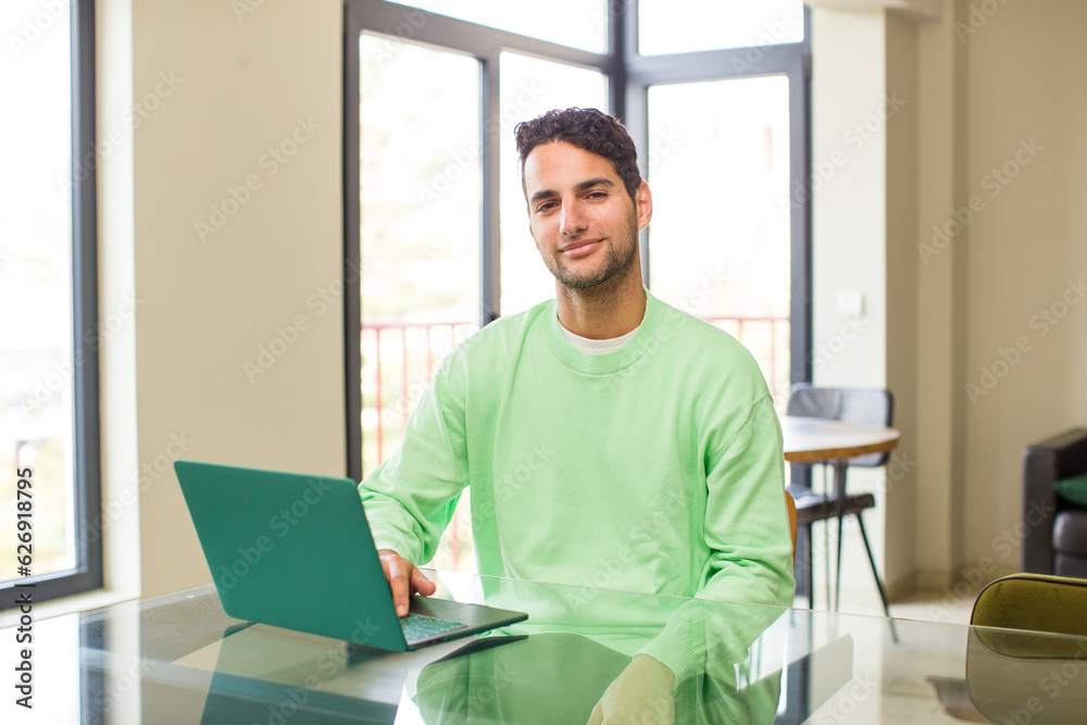 young hispanic man smiling happily with a hand on hip and confident, positive, proud and friendly attitude. working at home young hispanic man smiling happily with a hand on hip and confident, positive, proud and friendly attitude. working at home