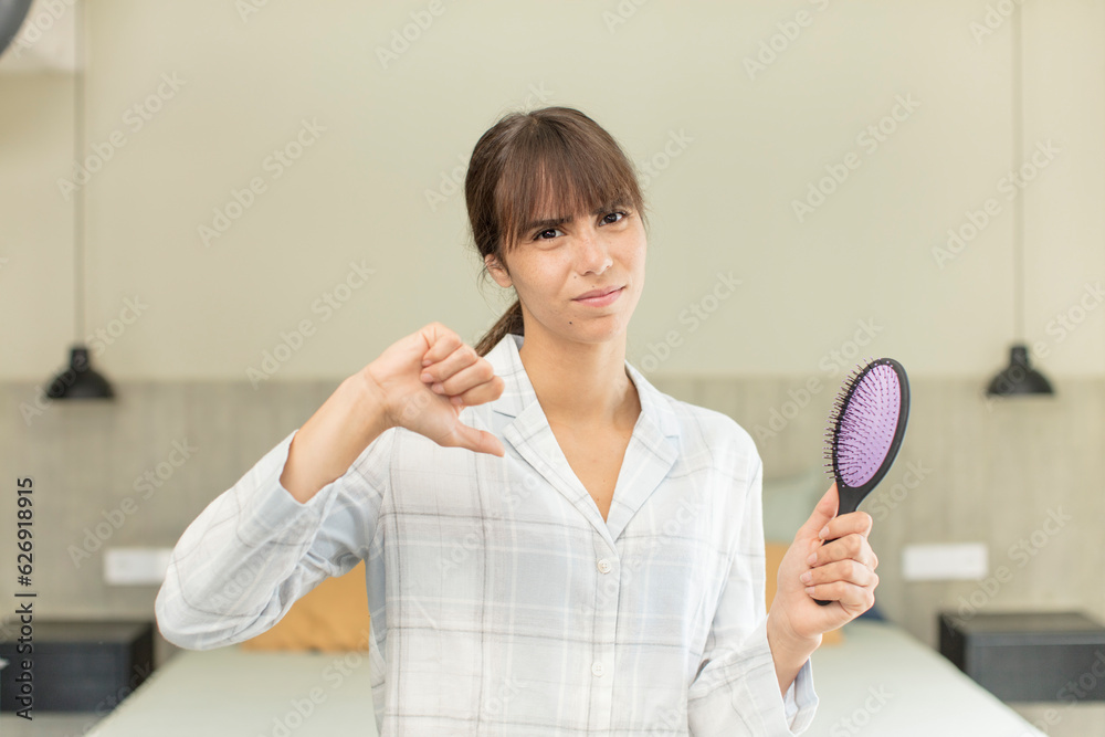 young pretty woman feeling cross,showing thumbs down. hair comb concept young pretty woman feeling cross,showing thumbs down. hair comb concept