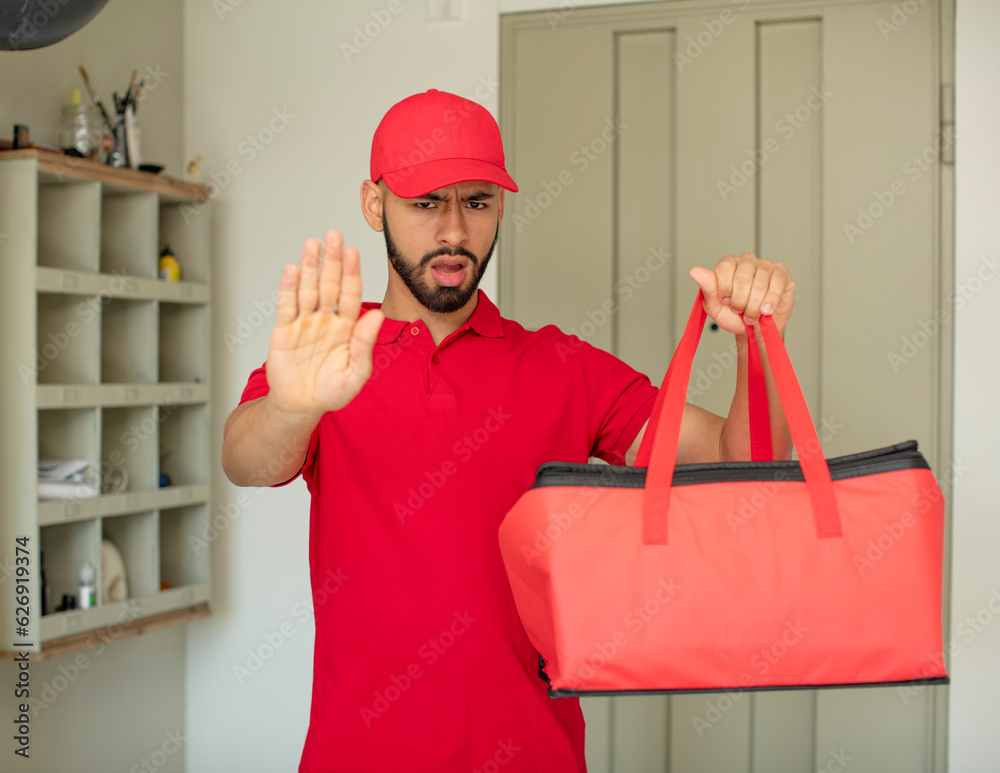 young adult man looking serious showing open palm making stop gesture. pizza deliveryman concept young adult man looking serious showing open palm making stop gesture. pizza deliveryman concept