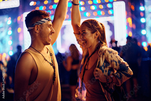 Carefree couple of festival goers dancing at summer music concert at night.