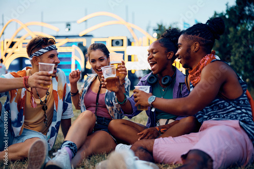 Cheerful friends toast with beer while attending summer music festival.