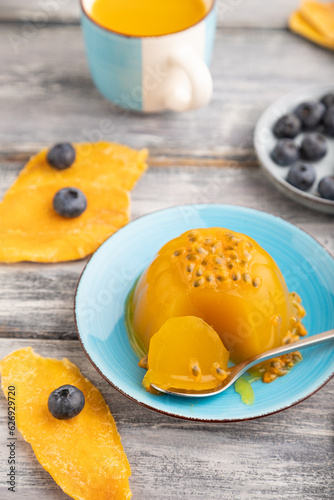 Mango and passion fruit jelly with blueberry on gray wooden, side view, selective focus.