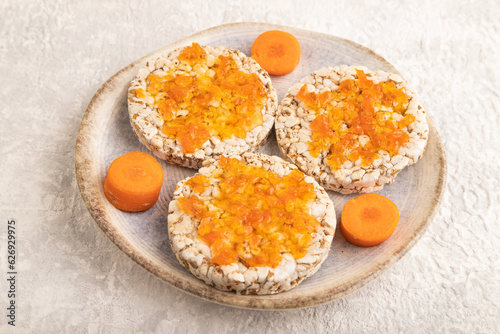Carrot jam with puffed rice cakes on gray concrete. Side view.
