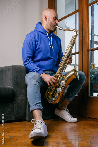 Canvas Print vertical portrait of young venezuelan man playing saxophone at home
