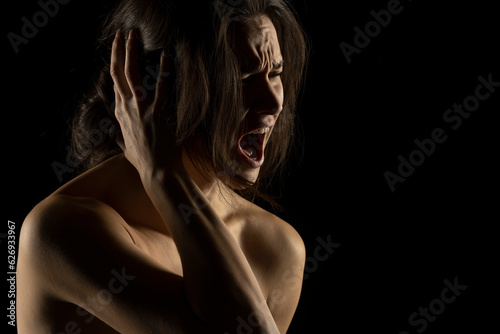 Silhouette of young unhappy screaming woman on black background