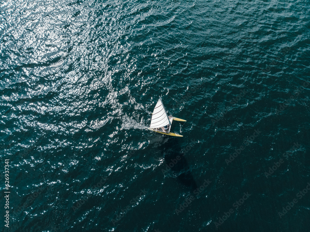 Drone shot from above of a catamaran in dark blue open waters