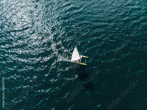 Drone shot from above of a catamaran in dark blue open waters