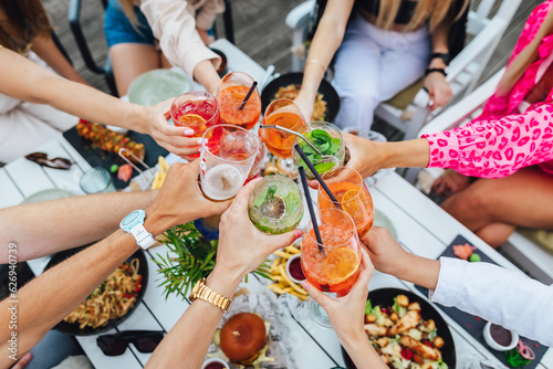 Billede på lærred Group of friends toasting multicolored cocktails at the summer terrace