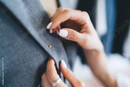 Crop woman fastening corsage pin to jacket
