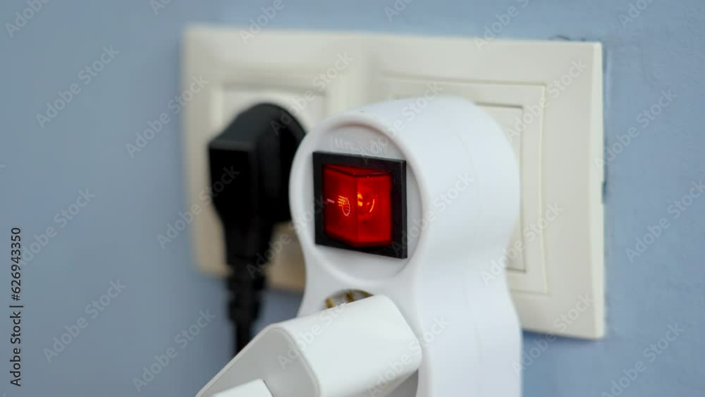 Turning on the red switch of the electrical splitter in wall outlet close up. Home power supply concept