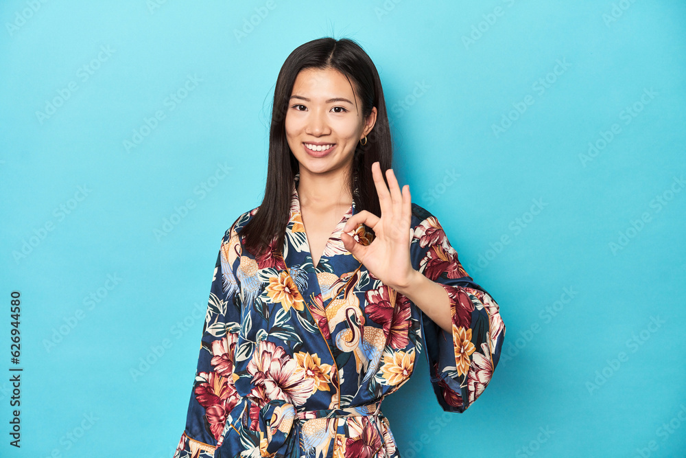 Elegant young Asian woman in kimono, studio shot cheerful and confident showing ok gesture. Elegant young Asian woman in kimono, studio shot cheerful and confident showing ok gesture.