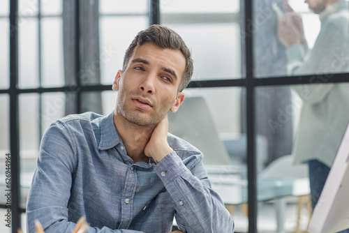 thoughtful male employee thinking over an idea while sitting at a desk in the office