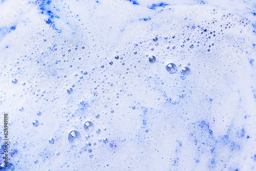 Foam of blue bath bomb dissolved in water. Soap sud background. Abstract soap foam texture.