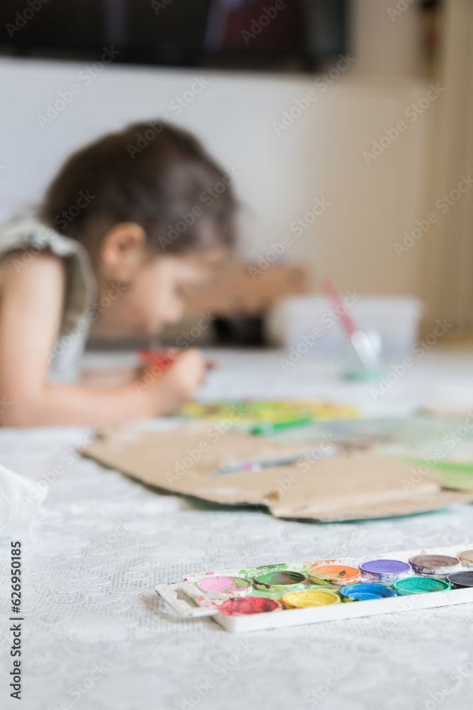 Sweet little girl playing with paints. Child exploring his creativity by painting with watercolors in a home environment. Sweet little girl playing with paints. Child exploring his creativity by painting with watercolors in a home environment.