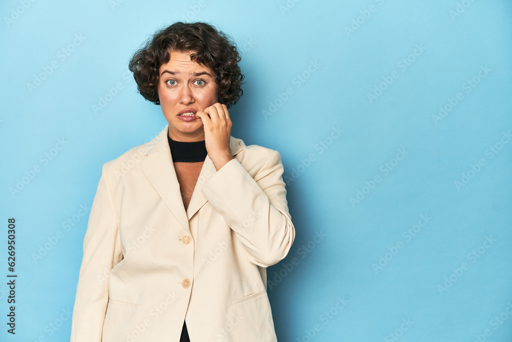 Young woman in elegant white blazer biting fingernails, nervous and very anxious.