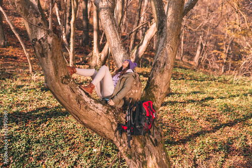 Woman relaxing in the tree while spending autumn day in the forest
