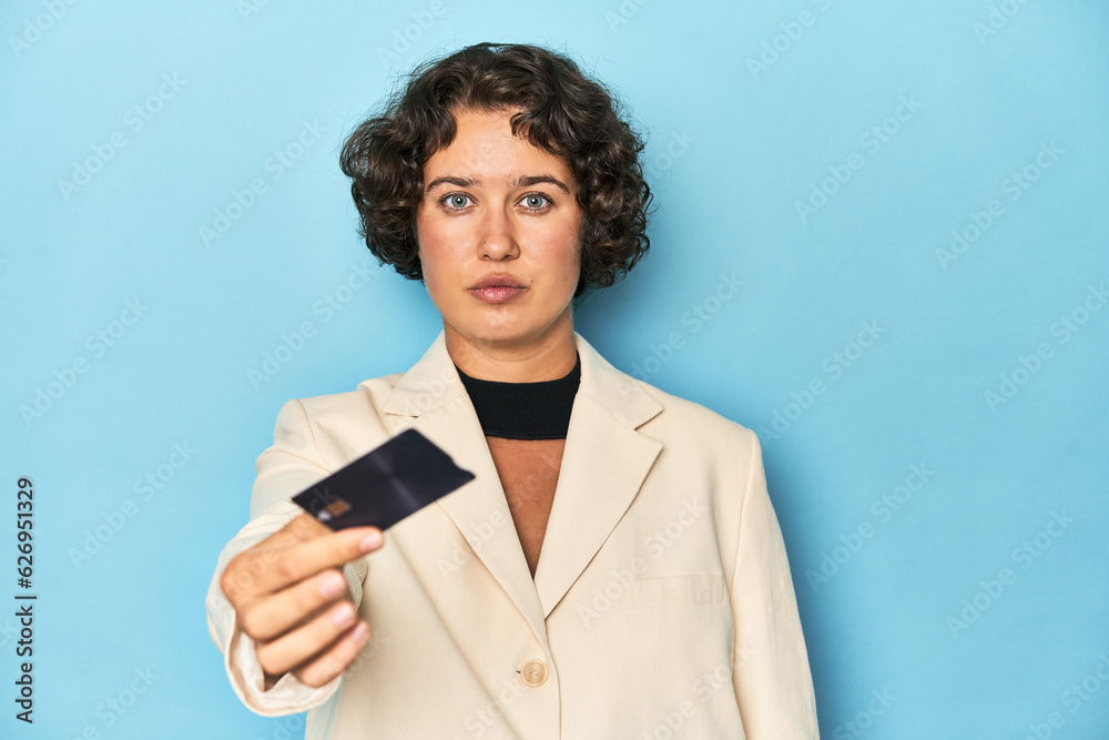 Young woman in white suit blazer holding a credit card, studio shot. Young woman in white suit blazer holding a credit card, studio shot.
