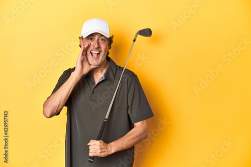 Middle-aged golfer with club and cap on yellow shouting and holding palm near opened mouth.