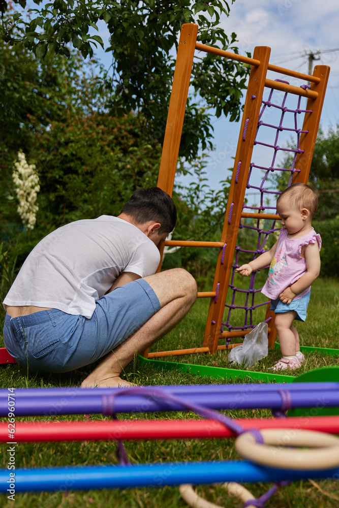 Fototapeta premium Dad with little daughter collects home sports complex outdoor.