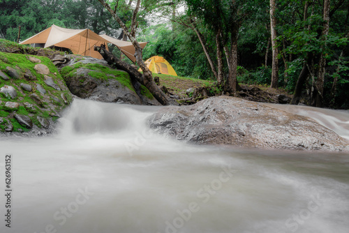 Campground Outdoor tent camping picnic group waterfall zone, equipment, natural camping area landscape background, with trees and green grass, summer trip relax and holiday Adventure Travel concept