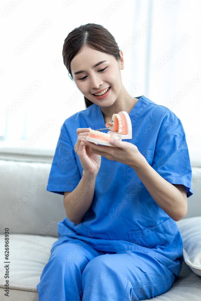 A Dentist holds denture model mouth mirror for teaches elderly woman how to take care of her oral health. new normal of medical treatment, telehealth and telemedicine progress. check up Teeth A Dentist holds denture model mouth mirror for teaches elderly woman how to take care of her oral health. new normal of medical treatment, telehealth and telemedicine progress. check up Teeth