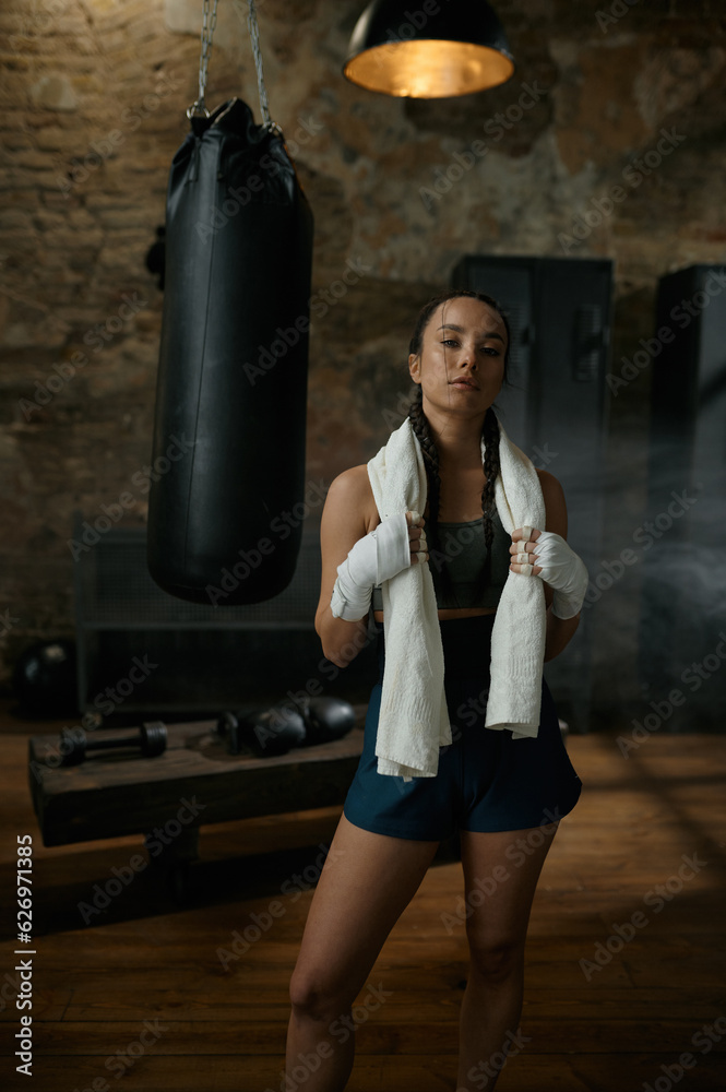 Satisfied woman boxer with towel on shoulders looking at camera