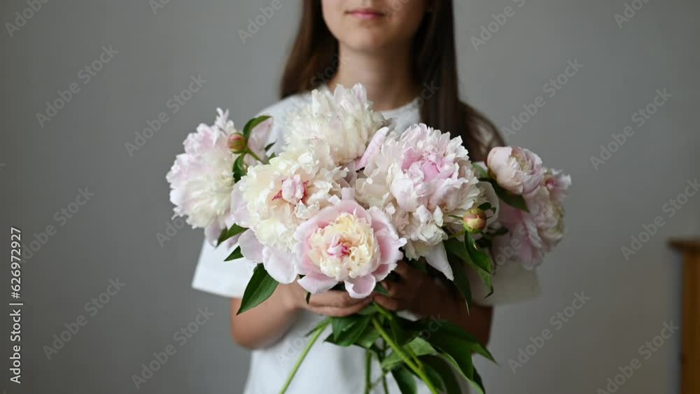 Anonymous girl child standing with blooming peony flower with stem Anonymous girl child standing with blooming peony flower with stem