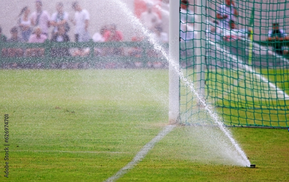 Water sprinklers watering a football or soccer field so that the pitch is in good condition. Space for text