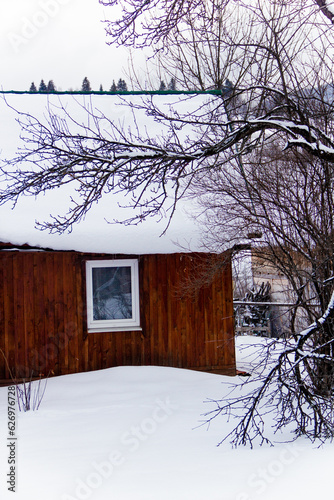 Wooden house with a window in a Ukrainian village in the mountains in winter under a large layer of white snow. Christmas photo