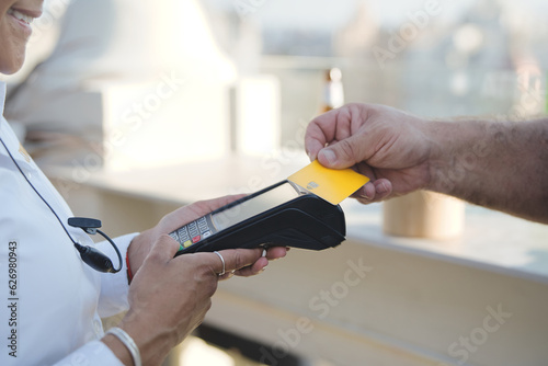 Hand of a Caucasian man approaching a yellow credit card to a dataphone. Concept of contacless payment. photo